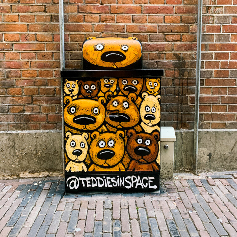 A electricity box with a drawing of a bunch of bears on it who all look at the camera. The bears look very similar and have a suprised expression on their face.