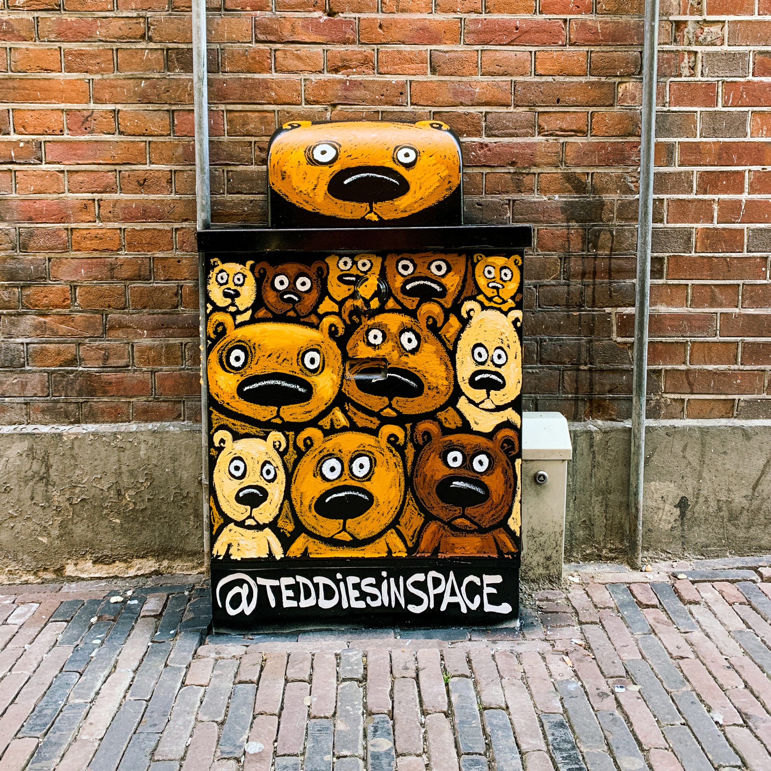 A electricity box with a drawing of a bunch of bears on it who all look at the camera. The bears look very similar and have a suprised expression on their face.