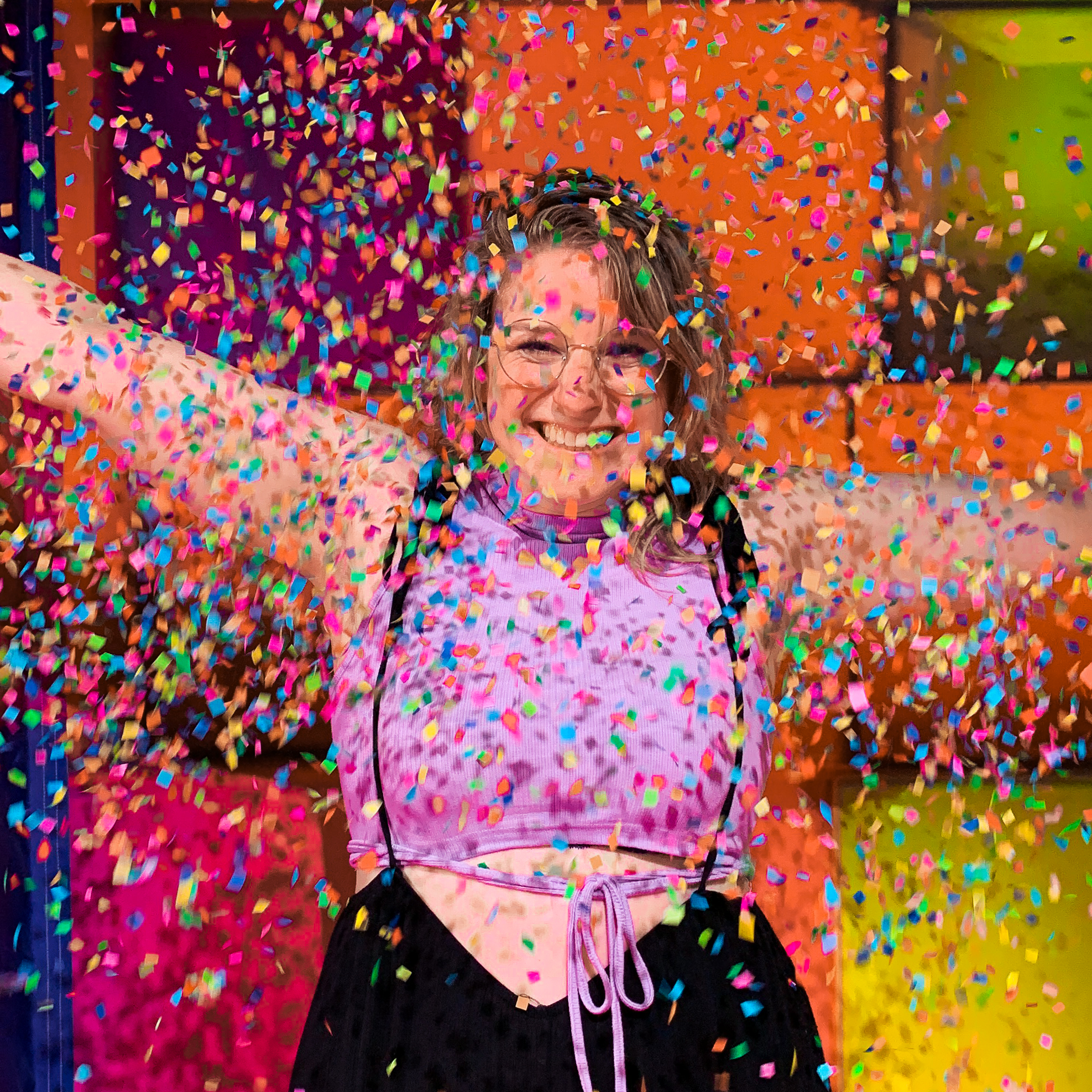 Wendy smiling at the camera, her arms spread out, while colorful confetti flies all around her.