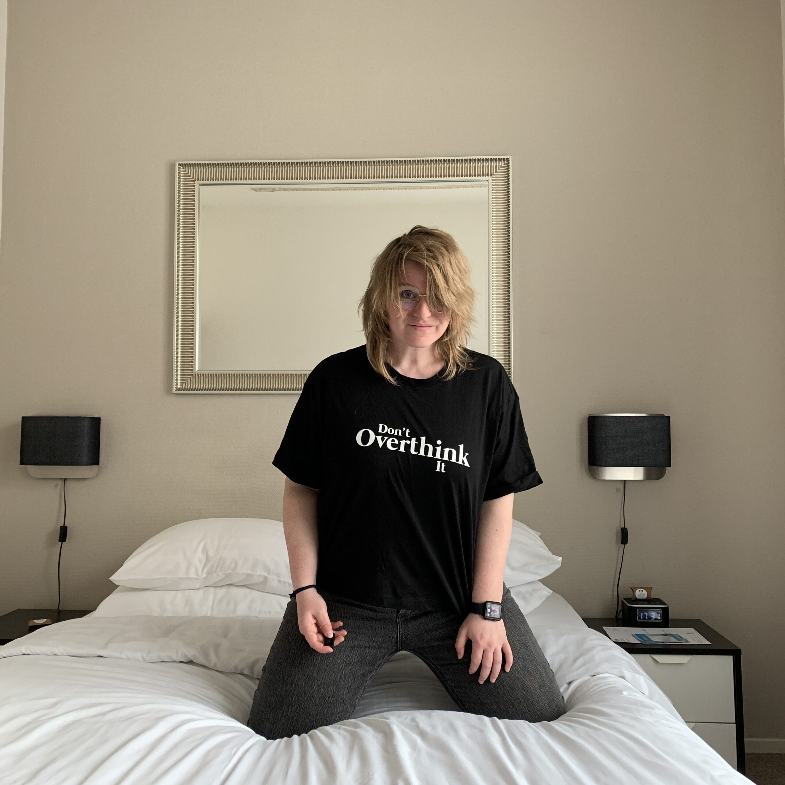 Wendy on a bed, looking at the camera with a shirt that says 'Don't overthink it'